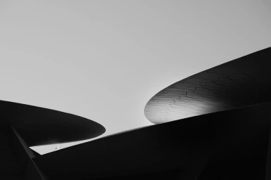 Architectural photography of curved metallic disc structures against a bright sky by Nick Meek