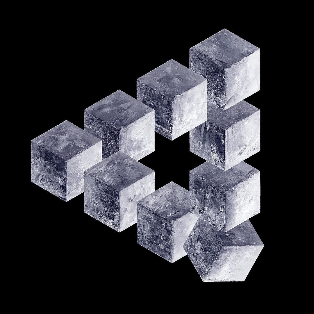 Optical illusion with gray cubes arranged in a Penrose triangle against a black background, creating a visually perplexing geometric artwork.