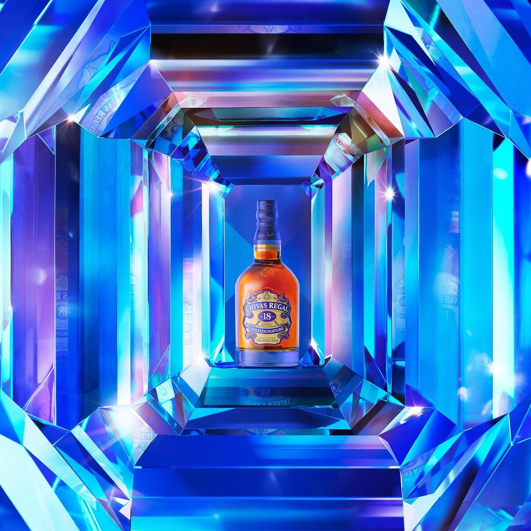 Chivas Regal 18 bottle showcased in a geometric, crystal-like blue setting with sharp angles and bright lighting for a luxury product shot.
