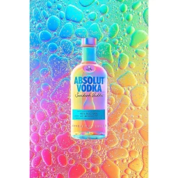 An Absolut Vodka bottle centered against a vibrant iridescent background covered in glossy colorful water droplets.