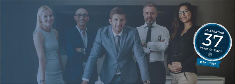 Five corporate professionals in business attire pose together in an office with a 37th anniversary badge graphic overlay.
