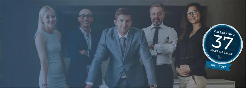 Five corporate professionals in business attire pose together in an office with a 37th anniversary badge graphic overlay.