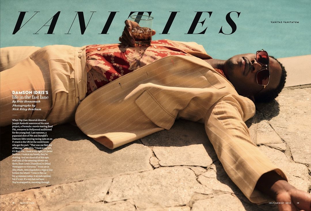 Damson Idris lounges poolside in a beige suit and patterned shirt, holding a drink, featured in a fashion editorial for Vanity Fair.