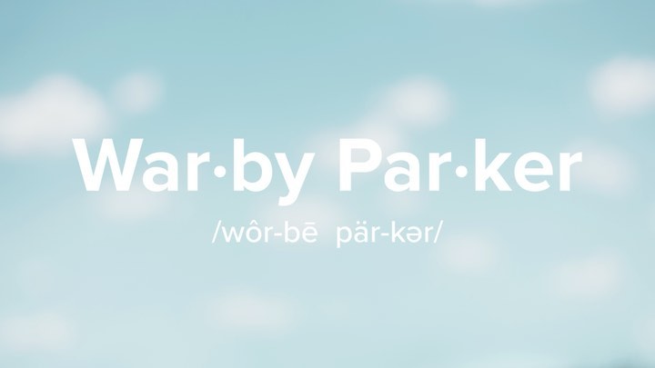 Warby Parker logo in white set against a blurred, light blue sky with soft cloud patterns, creating a clean and airy visual.