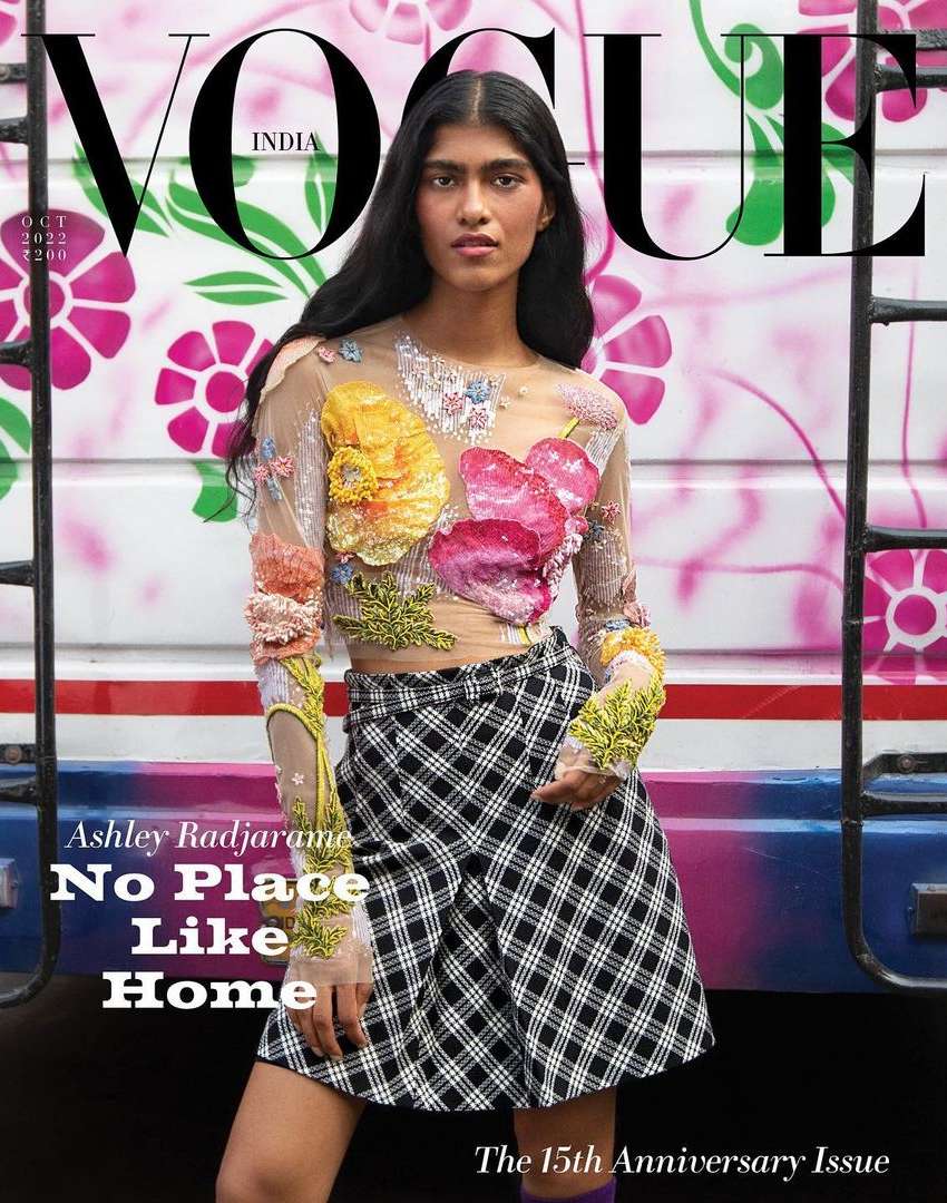 Vogue India cover featuring a South Asian female model in a floral top and plaid skirt, posing in front of a decorated bus.