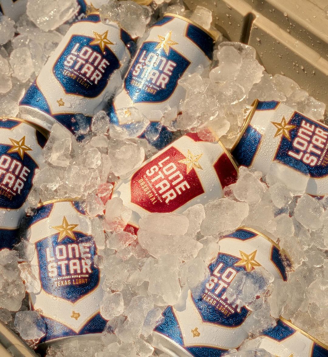 Several cans of Lone Star Texas Light beer are shown in a bin filled with crushed ice, creating a refreshing, thirst-quenching image.