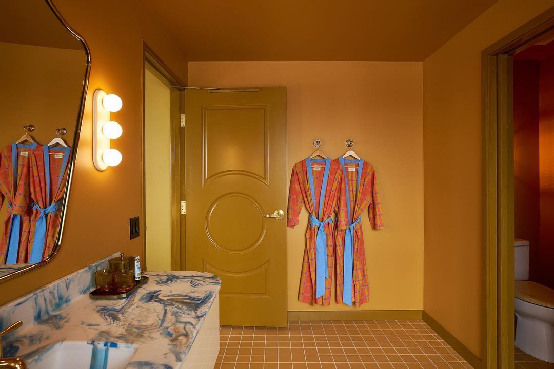 Stylish bathroom interior with marble countertop, modern lighting, and colorful bathrobes creating a vibrant and inviting hotel aesthetic.