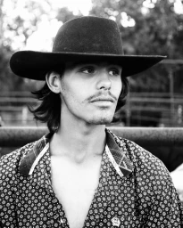 Monochrome portrait of a young man wearing a wide-brimmed cowboy hat and a patterned button-down shirt by Nick Turner in Paris.