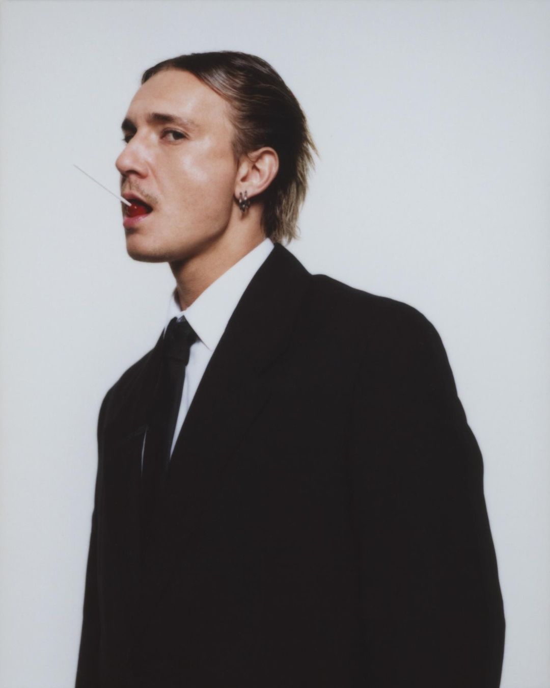 Stylish adult male in a suit with fair skin posing indoors against a neutral backdrop, showcasing fashion and portrait photography.