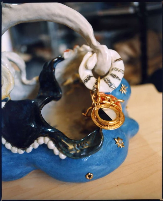 Close-up shot of a handmade ceramic basket with a ring attached, showcasing artistic craftsmanship and unique design.