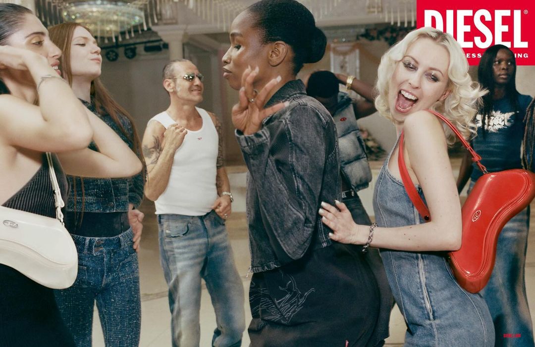 A group of diverse adults in an indoor space are dressed in denim clothing, and posing with Diesel brand fashion accessories in a group.