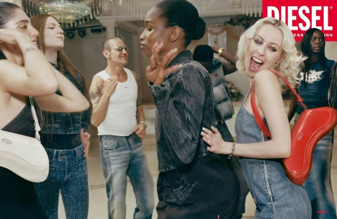 A group of diverse adults in an indoor space are dressed in denim clothing, and posing with Diesel brand fashion accessories in a group.