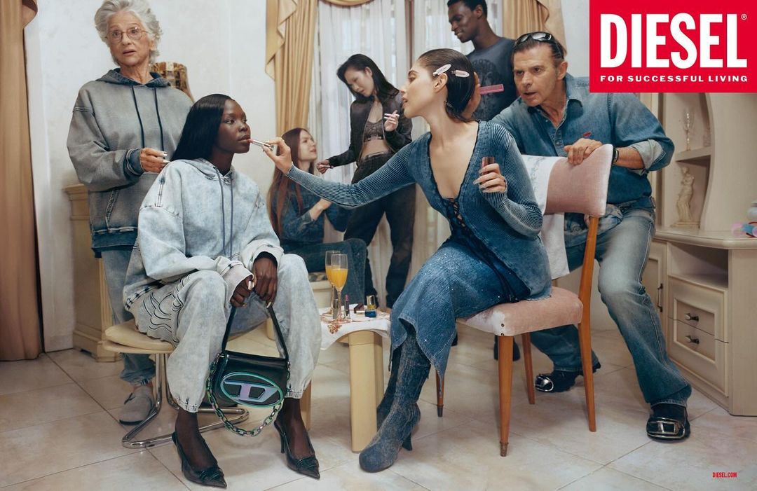 A group of diverse people in denim clothing gather indoors for a makeup session, featuring Diesel branding, warm lighting, and casual style.