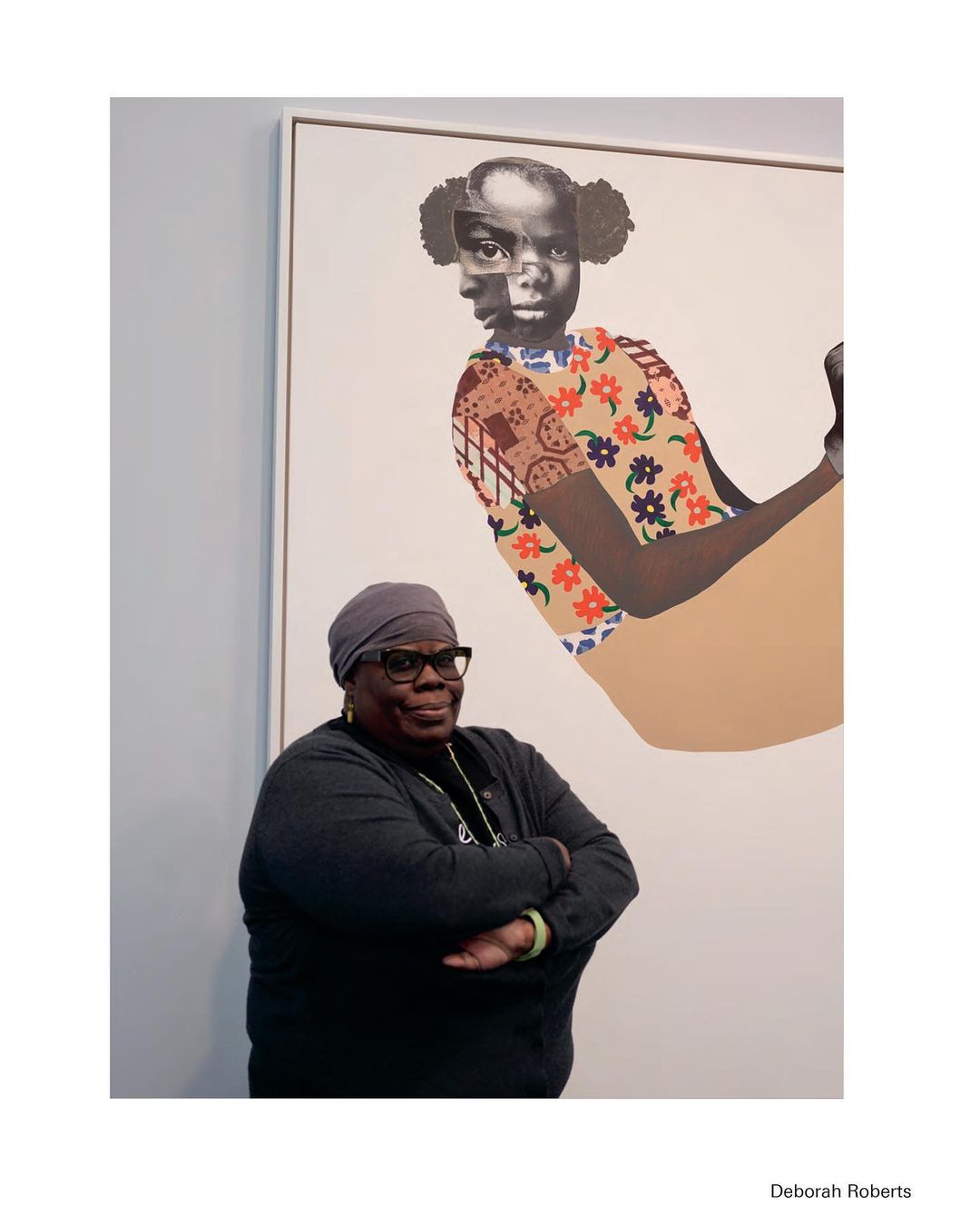 A woman with a gray head covering poses in front of a large collage of a girl made of cut paper and photographs in an art gallery.
