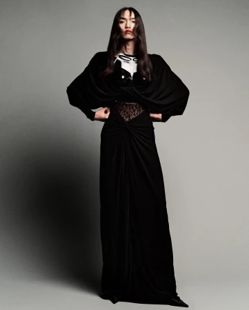Full-length shot of an Asian fashion model in a black floor-length gown with an embellished top, striking a pose in a photo studio.