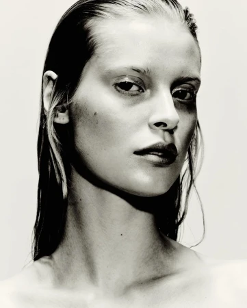 Close up portrait of a woman with wet hair and a serious expression against a plain white background