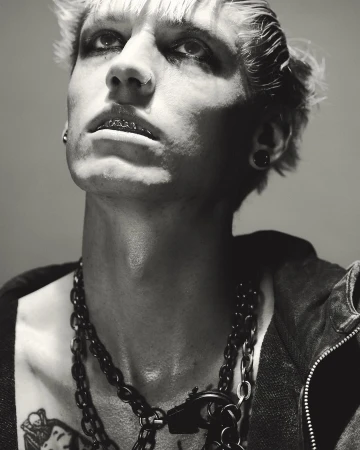 Portrait of a man with dyed blonde hair, dark eye makeup, nose ring, and layered chain necklaces captured by Nick Yang in Paris.