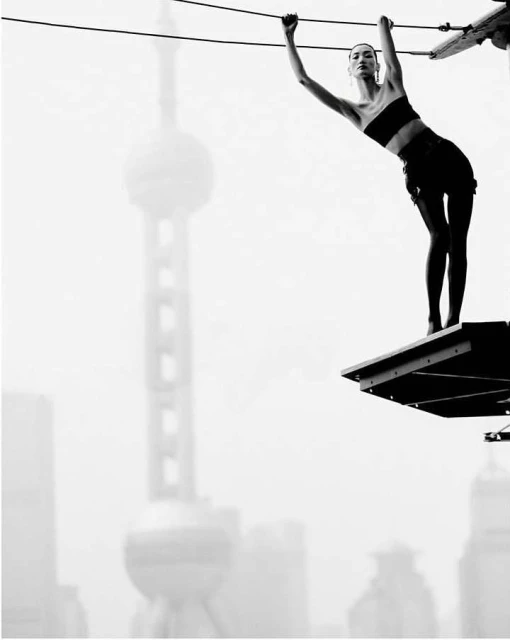 Woman in black sportswear on elevated platform with Shanghai skyline in background. Black and white fashion shot. Modern city architecture.