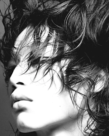 Close-up monochrome portrait of a person with dark wet messy hair falling across their face in Paris by Nick Yang