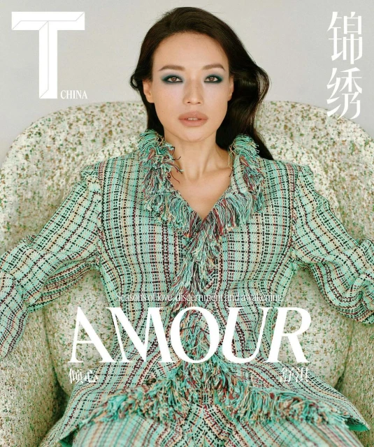 Fashion magazine cover featuring an adult female model in a plaid suit with fringe detail, seated on a patterned armchair with magazine logos and titles.