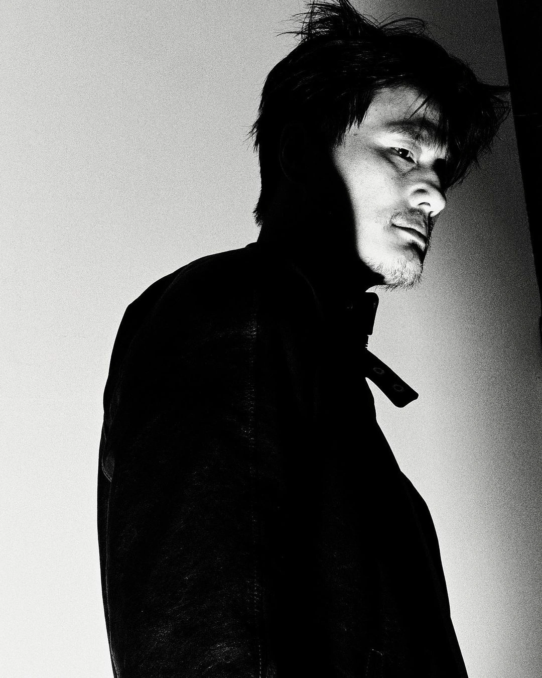 Monochrome portrait of an Asian man with dark hair in profile against a light background by Nick Yang
