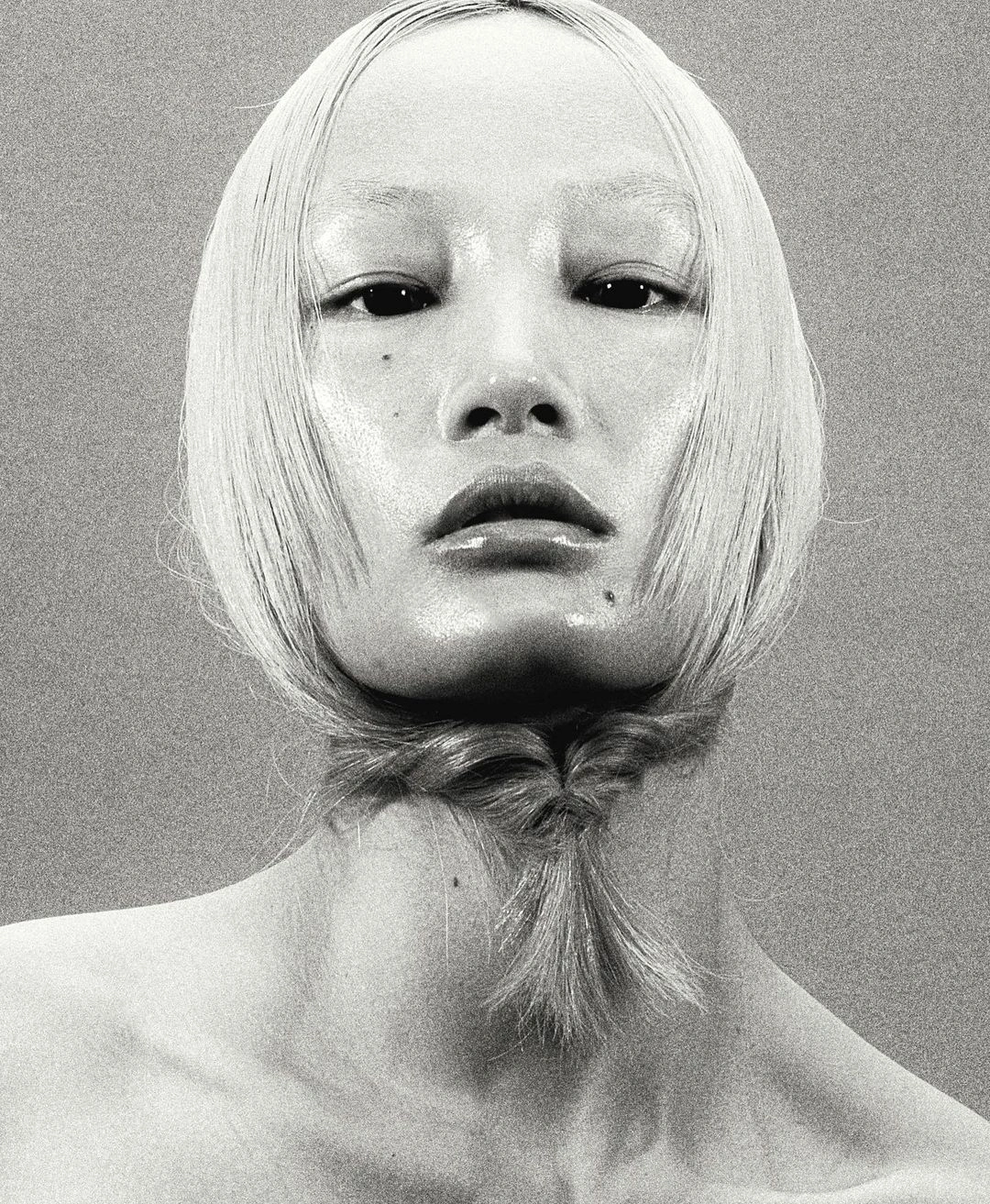Monochrome portrait of a model with blonde hair, bleached eyebrows, and a small braided section under the chin by Nick Yang in Paris.