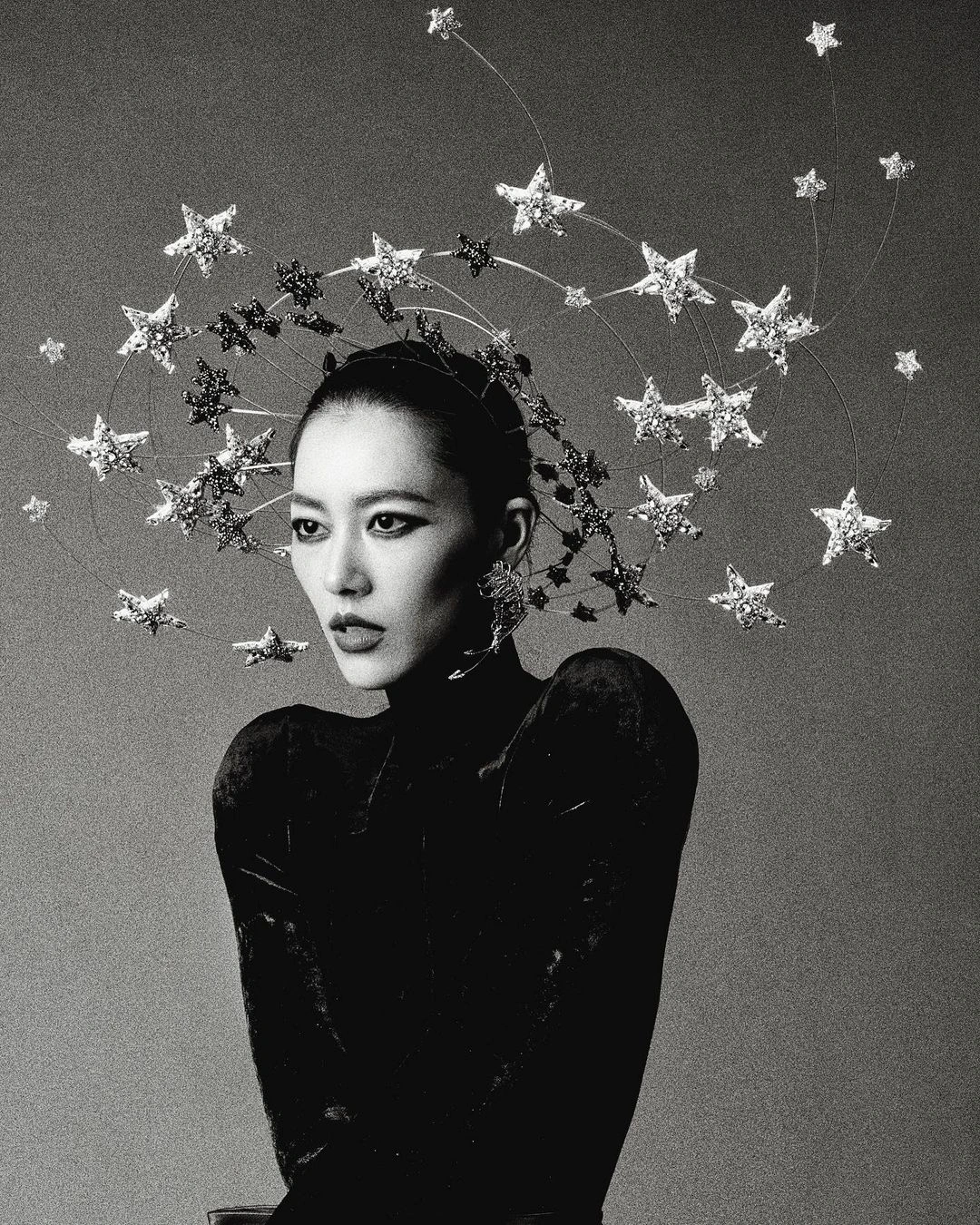 Monochrome portrait of an East Asian woman wearing a celestial star headdress and a dark structured top in Paris by Nick Yang