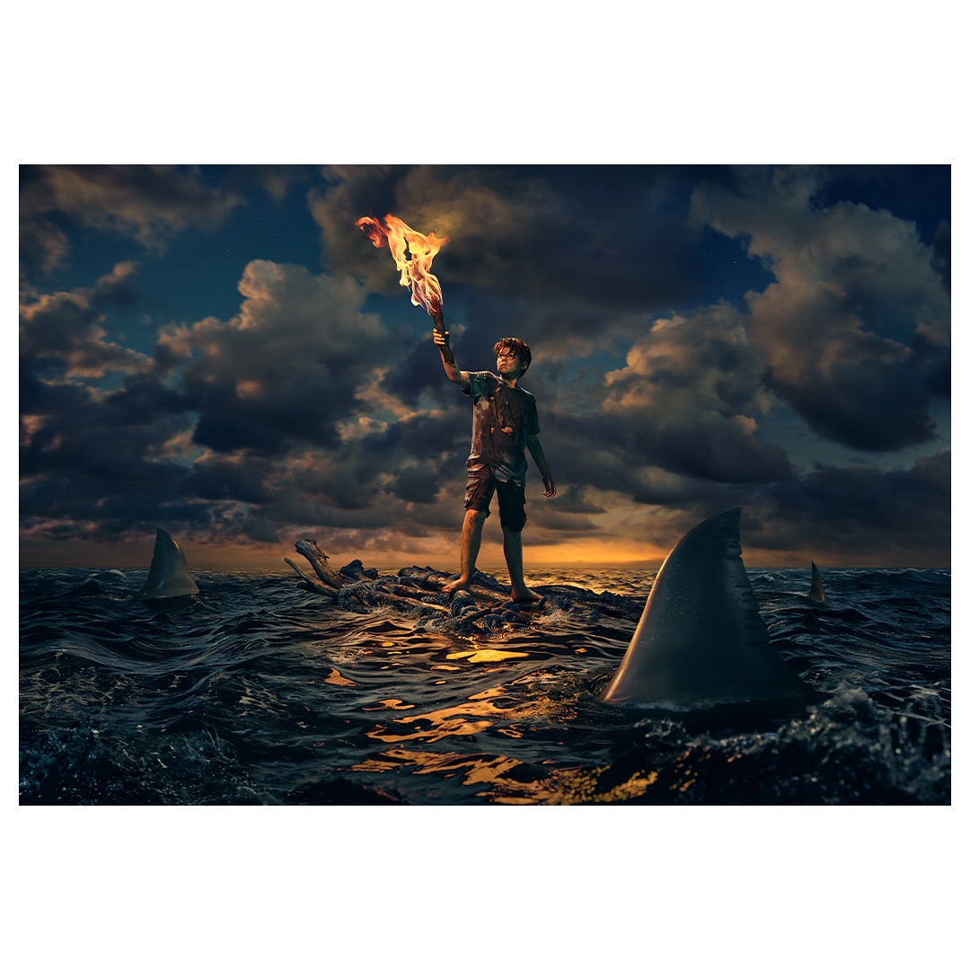 Young person stands on driftwood in stormy ocean surrounded by sharks, holding burning cloth aloft under dramatic sky with sunlit clouds.