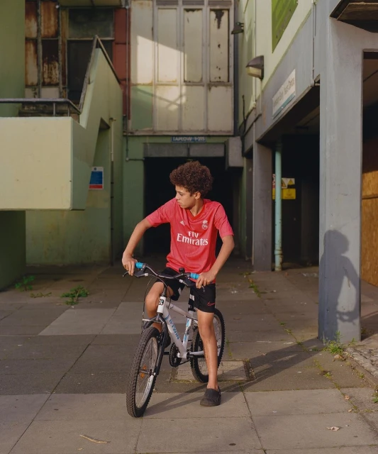 Young cyclist on a bicycle in an urban setting. Teenage boy pauses on his bike in an outdoor urban area, showcasing the city backdrop.