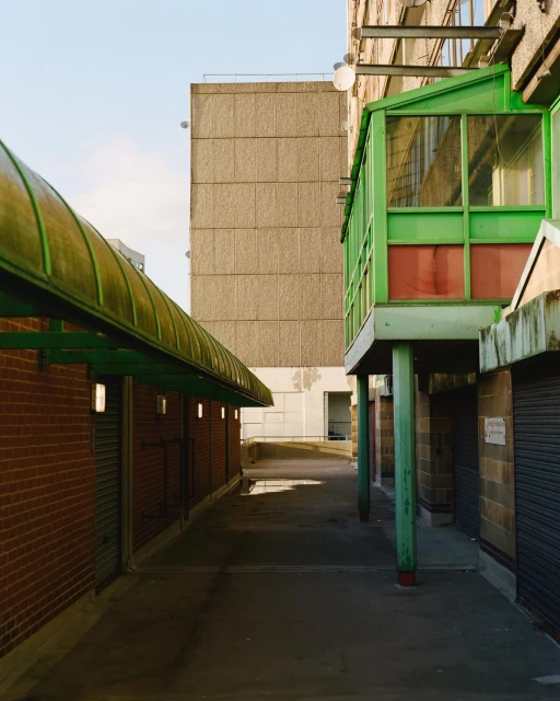 Urban landscape featuring a covered walkway alongside brick and concrete buildings under a clear sky during daylight hours. Architecture.
