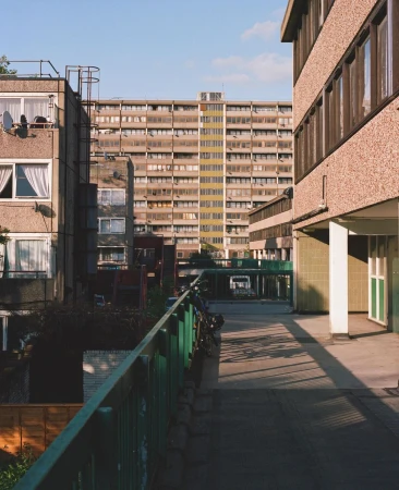 Exterior of a social housing complex featuring walkways and multiple apartment buildings under a clear blue sky during daytime.