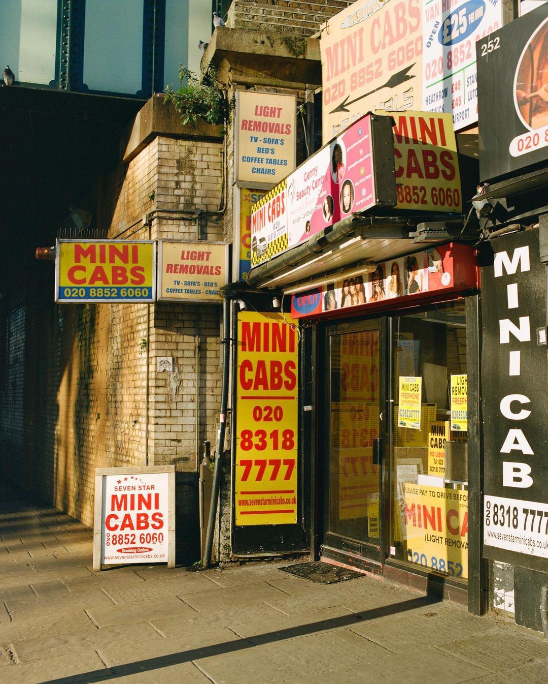 Multiple Mini Cab storefronts display signage and business information on a city street with brick architecture and pedestrian walkway.