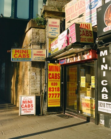 Multiple Mini Cab storefronts display signage and business information on a city street with brick architecture and pedestrian walkway.