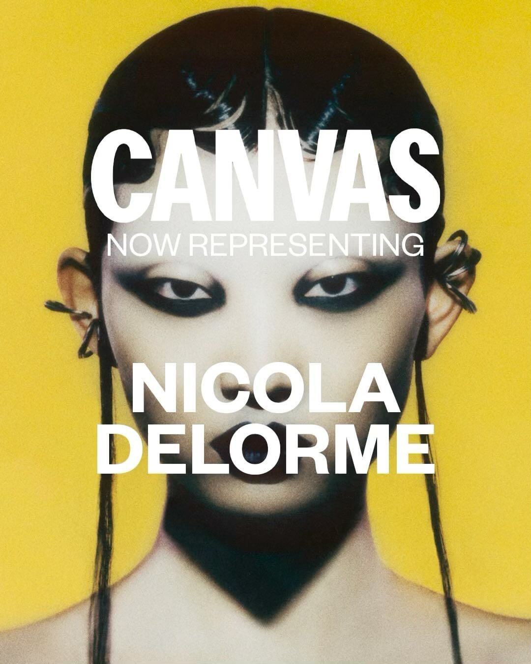 Striking portrait of a model with dark eye makeup and a futuristic hairstyle against a vibrant yellow background in a beauty campaign.