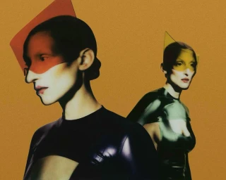 Two women wearing translucent geometric visors against a warm mustard yellow grainy background