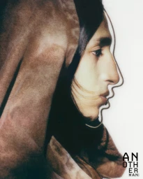 Profile portrait of a person in a brown hooded garment against a bright background with the Another Man magazine logo