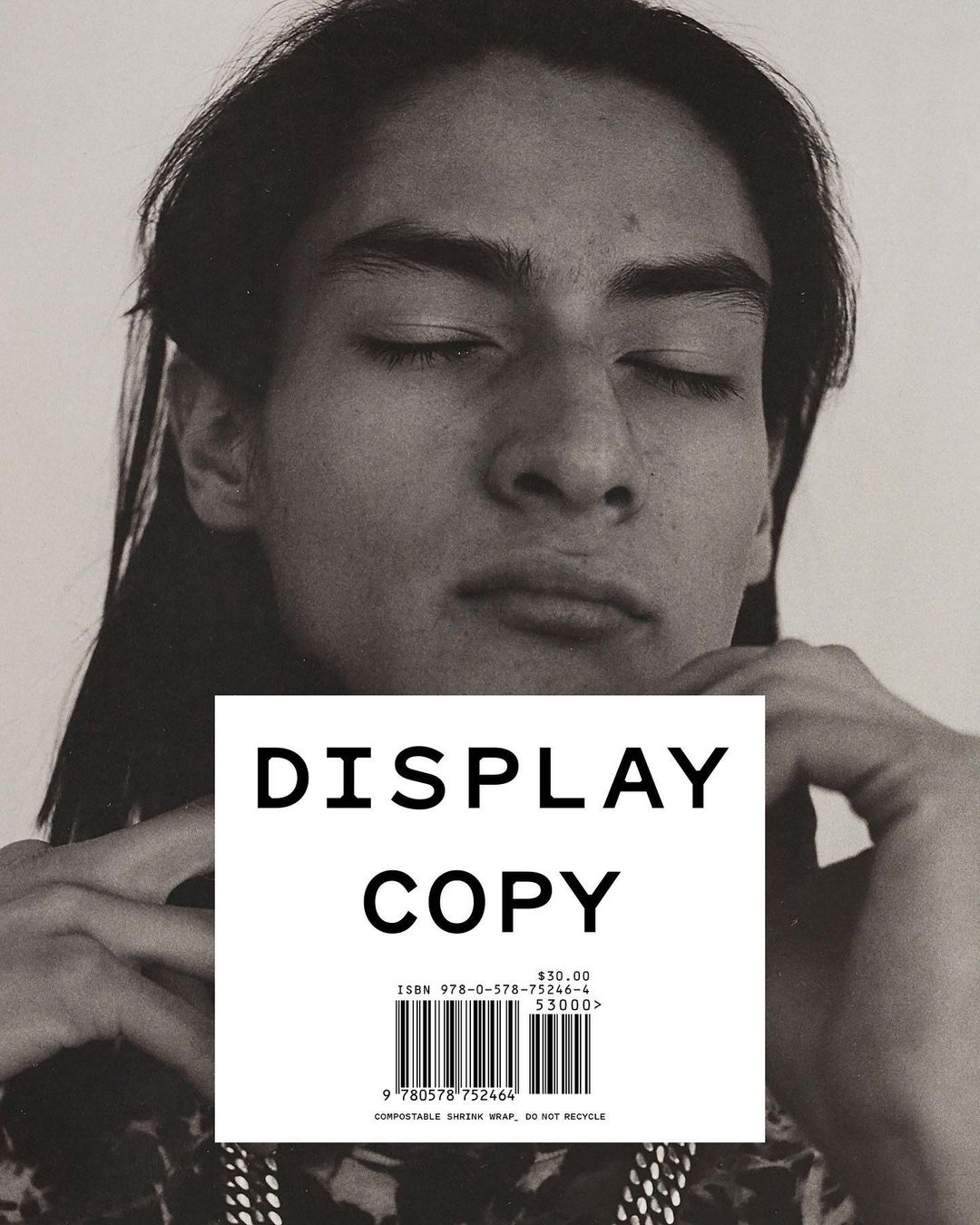 Portrait of a young adult with long dark hair and closed eyes, partially covered by a block of white paper with 'Display Copy' on it.