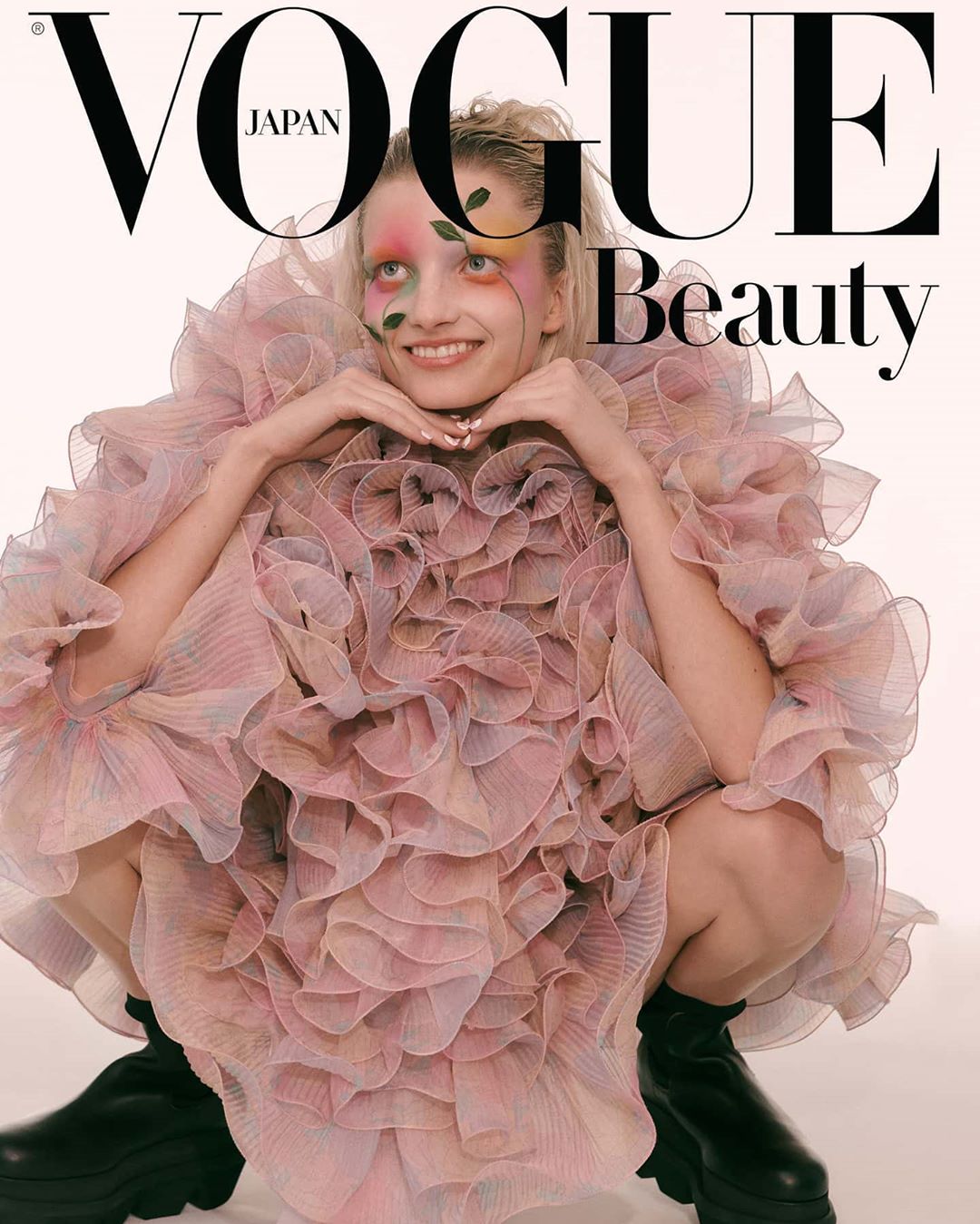 Vogue Japan cover featuring a young woman with floral face paint wearing a pink ruffled dress and black platform boots against a white background.