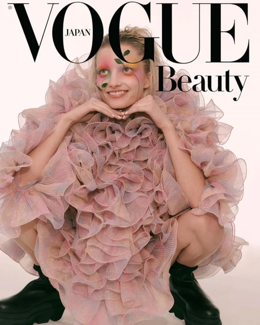 Vogue Japan cover featuring a young woman with floral face paint wearing a pink ruffled dress and black platform boots against a white background.
