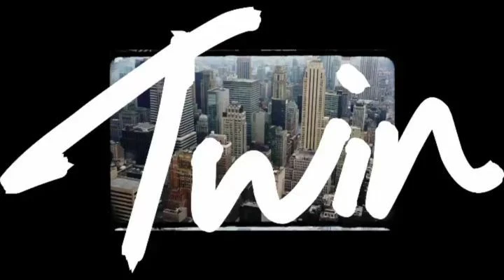 Cityscape view framed by the white handwritten word "Twin" against a black background, creating a stark contrast and urban aesthetic.