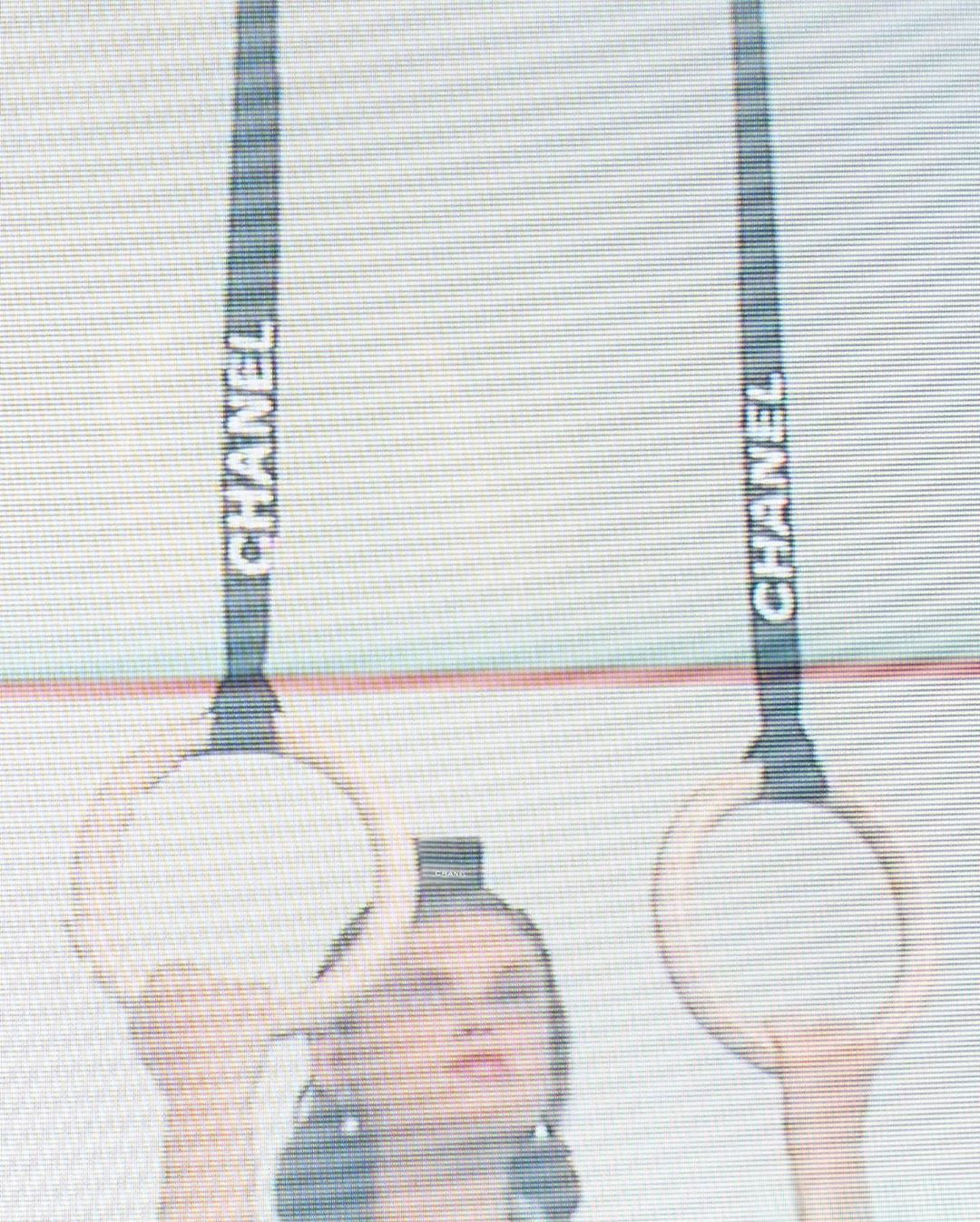 Woman performs on gymnastic rings in a fashion photoshoot. The logo for Chanel is visible on the black ring straps.