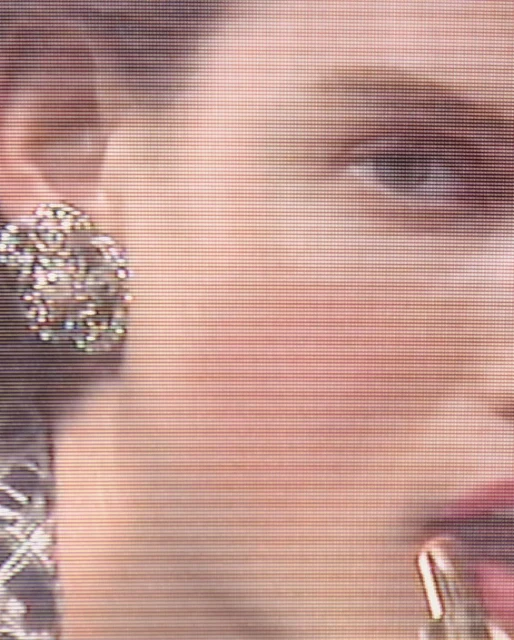 Close-up on a woman's face with an earring, showing a portion of her face including her eye, cheek, ear, and part of her mouth.