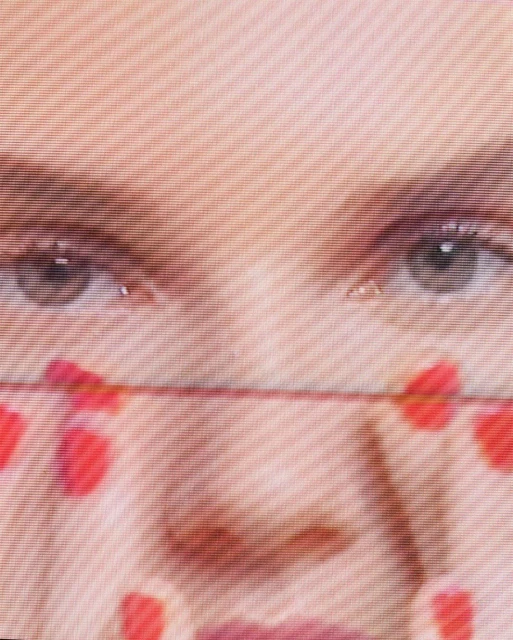 Close-up shot of a woman's face featuring her eyes and a mask with red heart patterns, creating a striking visual effect.