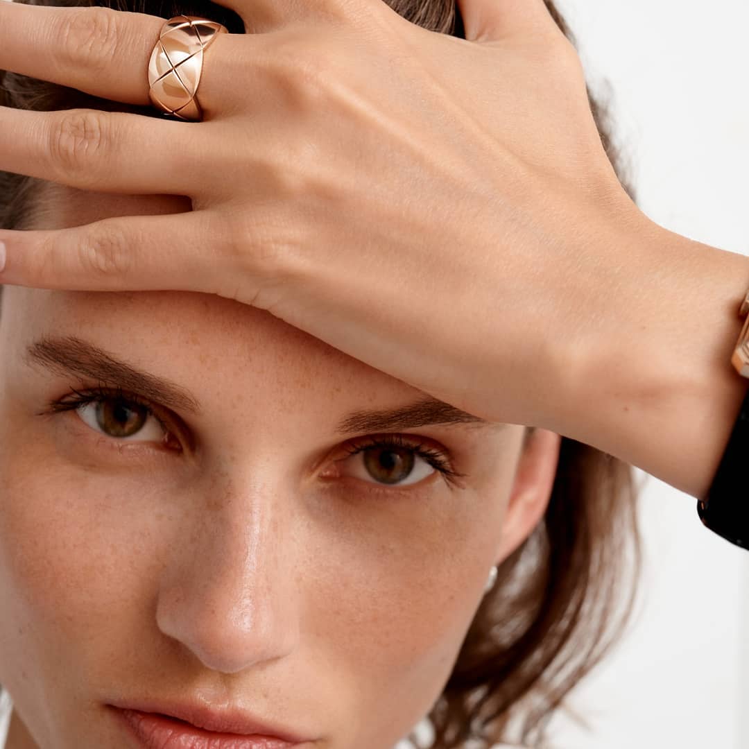 Close-up portrait of a woman with a wide quilted gold ring on her hand resting on her forehead, photographed by Nicolas Kantor.