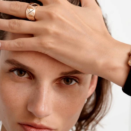 Close-up portrait of a woman with a wide quilted gold ring on her hand resting on her forehead, photographed by Nicolas Kantor.