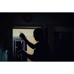 Silhouette of a man holding an IV drip bag in a dimly lit room in Paris