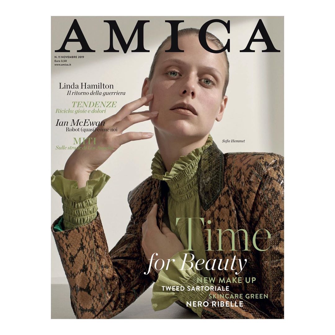 Magazine cover of Amica featuring a blonde woman wearing a patterned blazer, her hand near her face, with beauty related text.