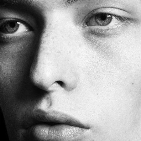 Extreme close-up monochrome portrait of a person's face focusing sharply on the eyes, nose, and lips.