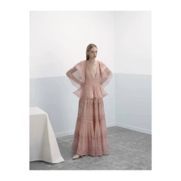Model in a tiered pink lace dress standing in a minimalist room with a draped table by Nicolas Valois