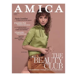 Model wearing a satin green top and studded headband posing against a solid pink background for an Amica magazine cover.